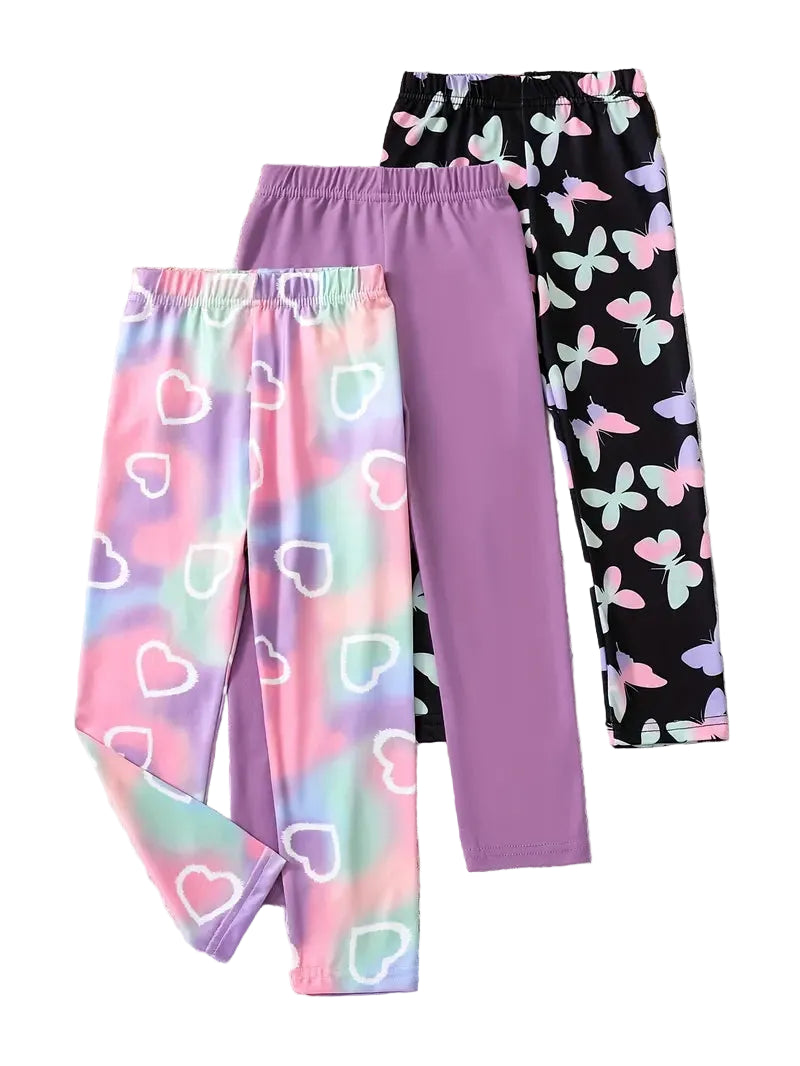 Three pairs of colorful pants with different patterns on a light wooden surface.