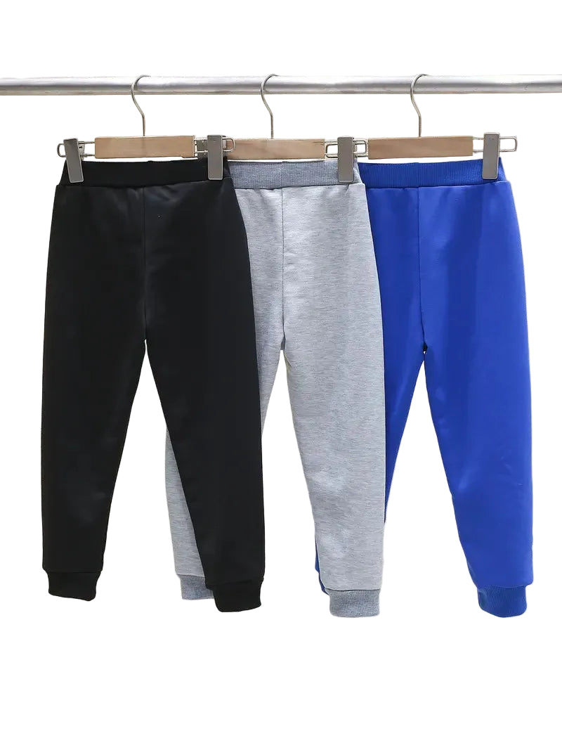 Three pairs of sweatpants in black, gray, and blue hanging on a rack.