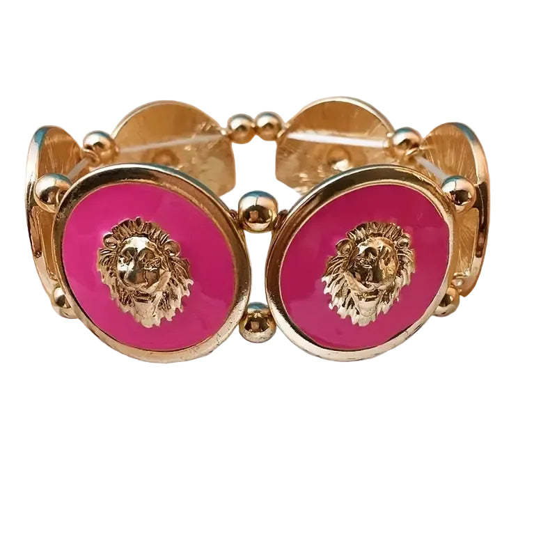 Gold bracelet with pink circular charms featuring lion heads on a white surface with black spots.