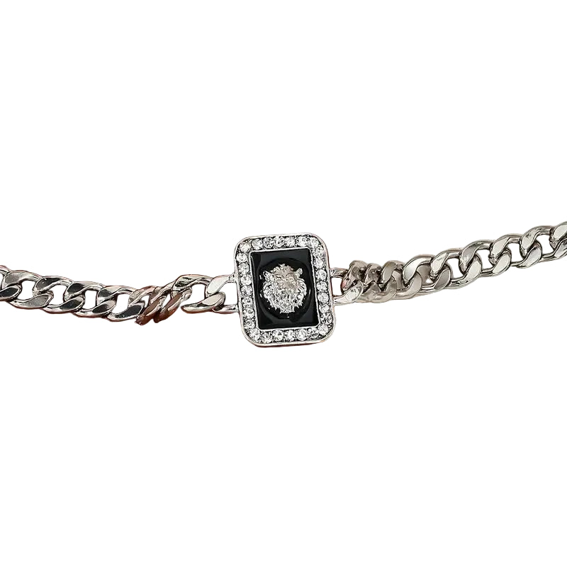 Silver chain bracelet with a black and white clasp on a textured surface