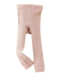 Pink ribbed tights on a light gray background with a small bag and toy.