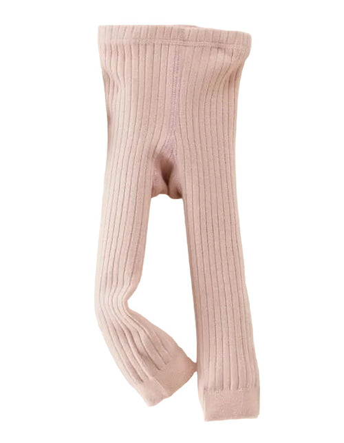 Pink ribbed tights on a light gray background with a small bag and toy.
