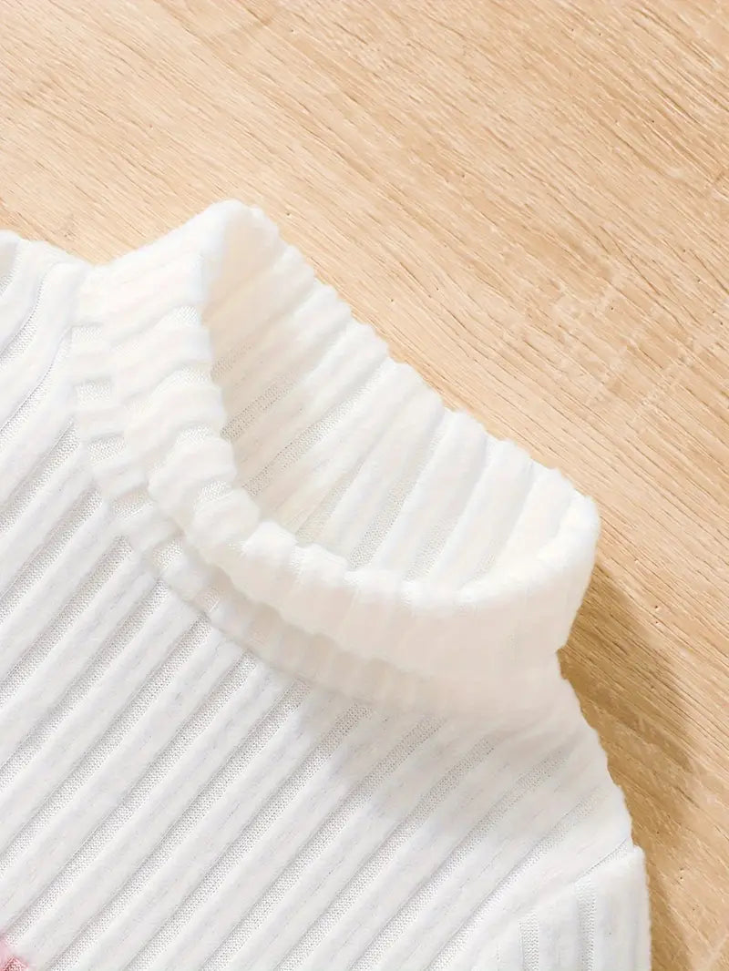 Close-up of a white ribbed sweater on a wooden surface