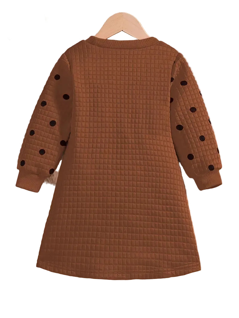 Brown checkered dress with black polka dots on a hanger against a white background