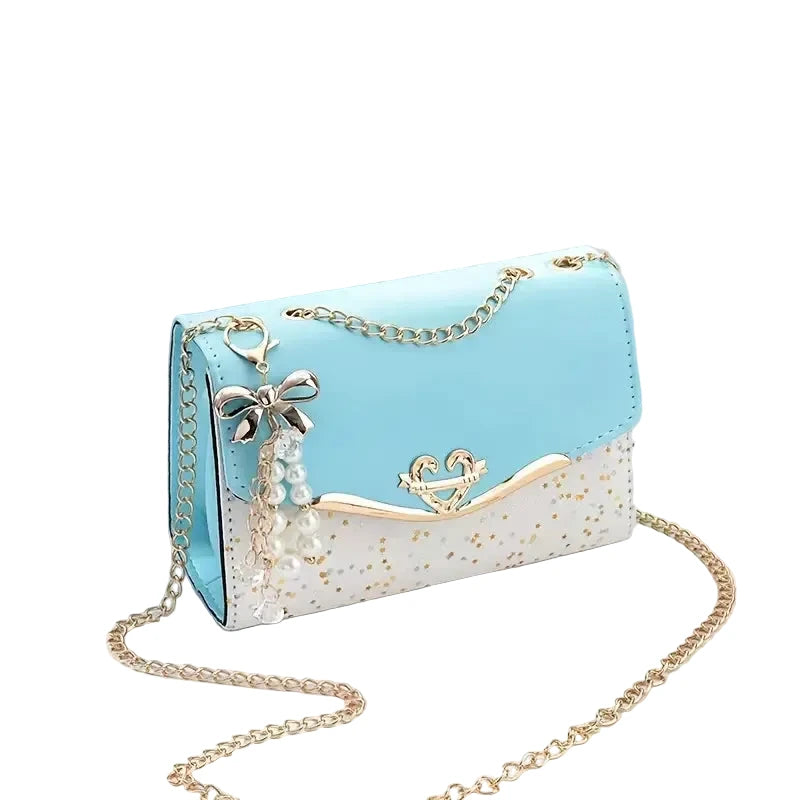 Light blue handbag with gold chain and decorative elements on a white surface.