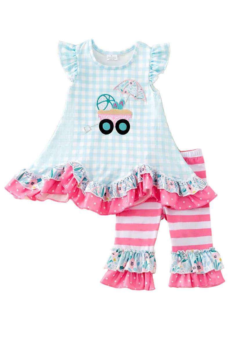 Children's outfit with a blue checkered top and pink striped pants on a fluffy white surface.