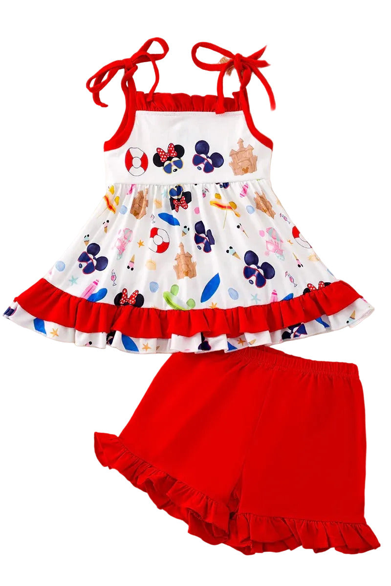 Children's outfit with a colorful top and red shorts on a fluffy white surface.