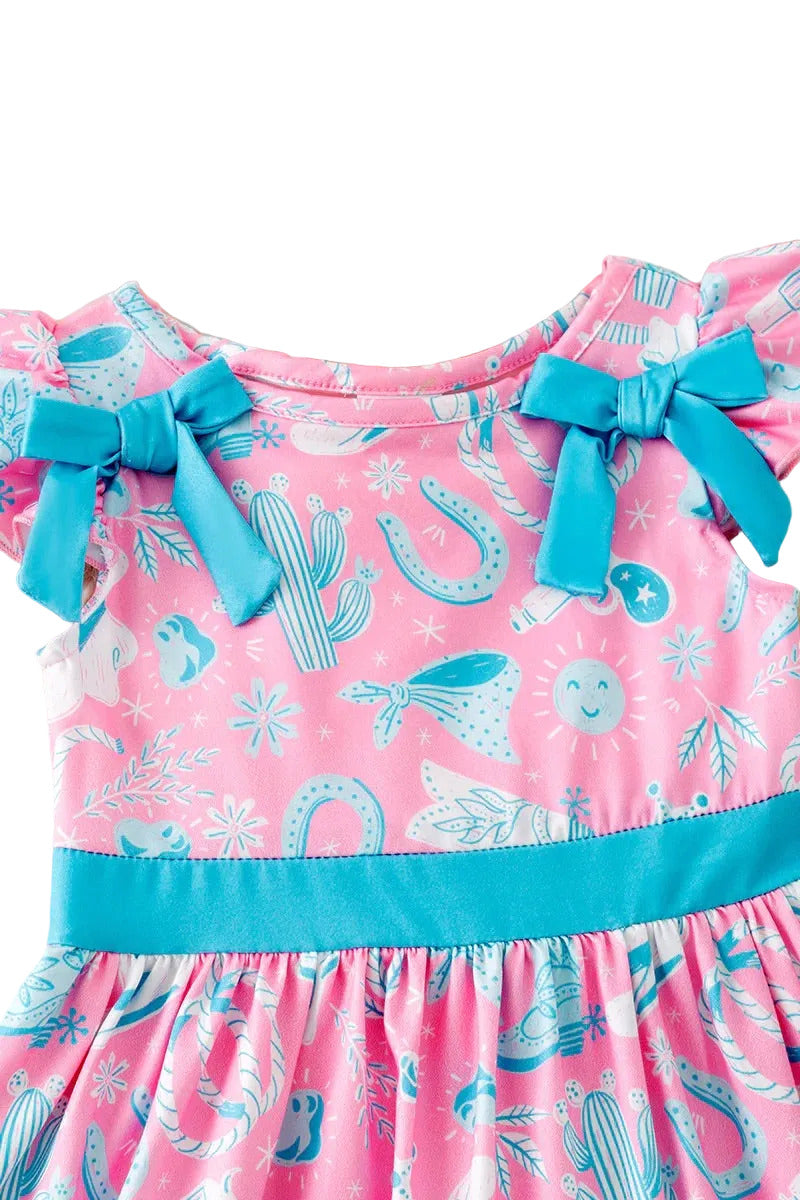 Pink dress with blue accents and cactus pattern on a fluffy white surface