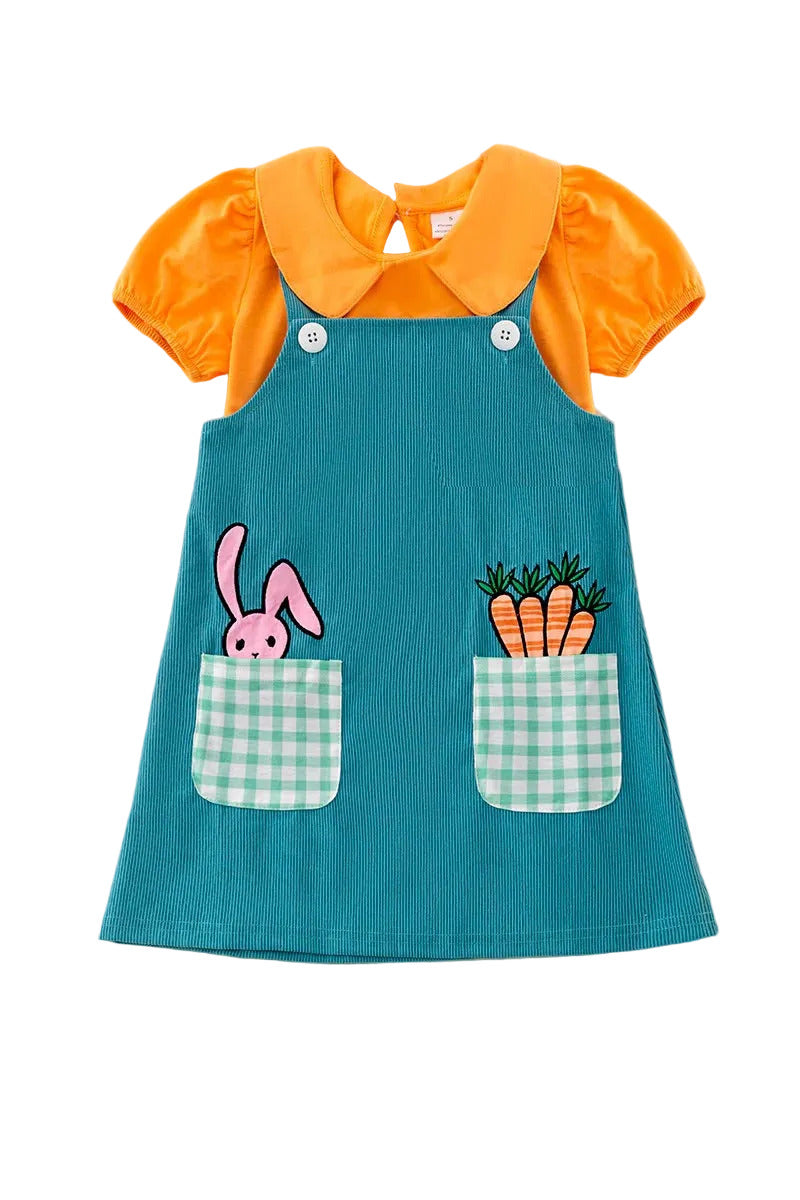 Teal dress with orange collar and bunny and carrot designs on a fluffy white surface
