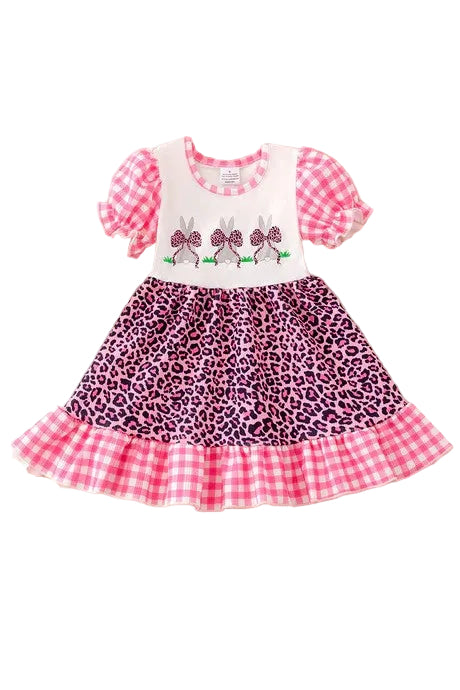 Children's dress with checkered top and leopard print skirt on a fluffy white surface.