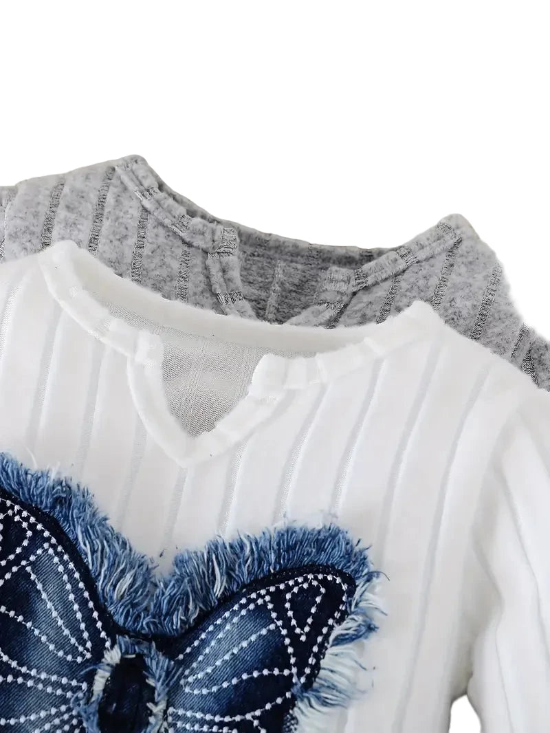 Close-up of a white sweater with blue denim bow detail on a white background