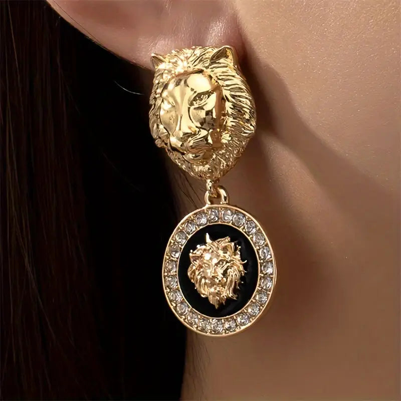 Gold lion-shaped earring with a black center and gemstones worn on an ear.