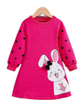 Pink dress with black polka dots and a bunny design on a hanger against a white background