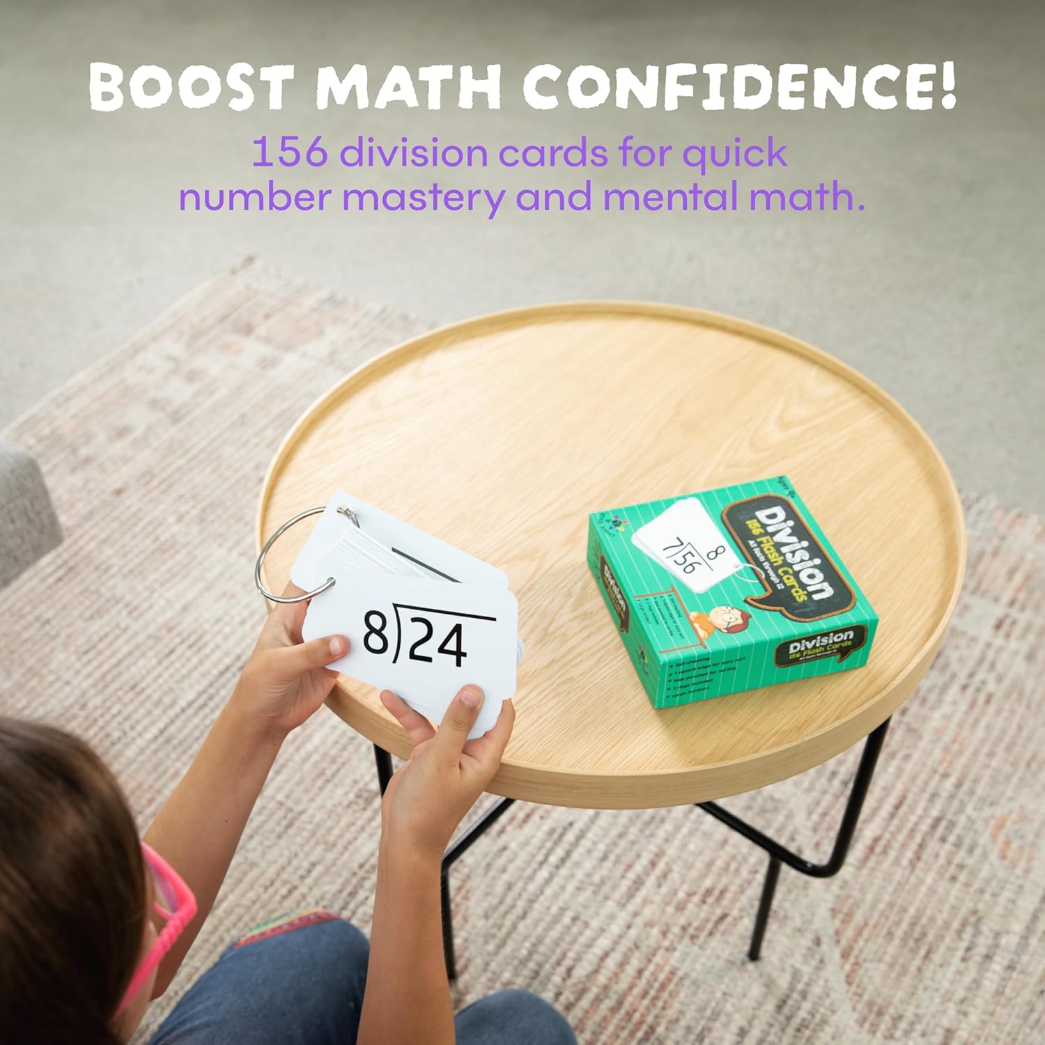 Person holding a division card with a box of division cards on a table, promoting math confidence.