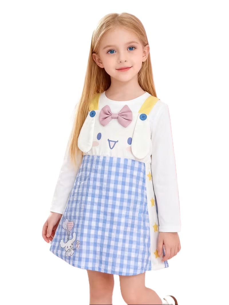 Young girl wearing a white shirt with a cartoon design, yellow suspenders, and a blue checkered skirt on a white background.