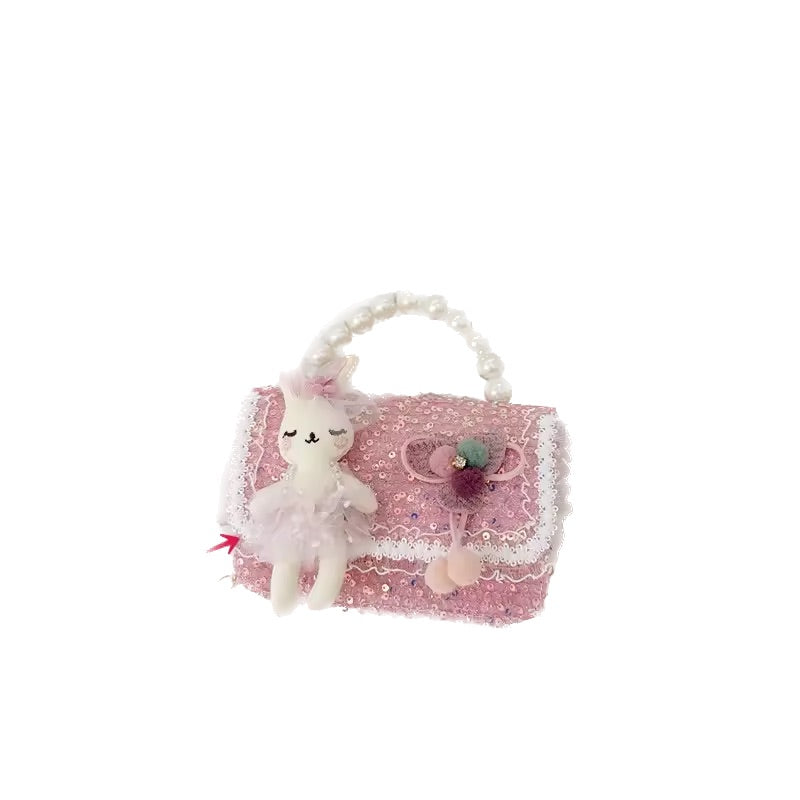 Pink sequined handbag with a plush toy on a white background