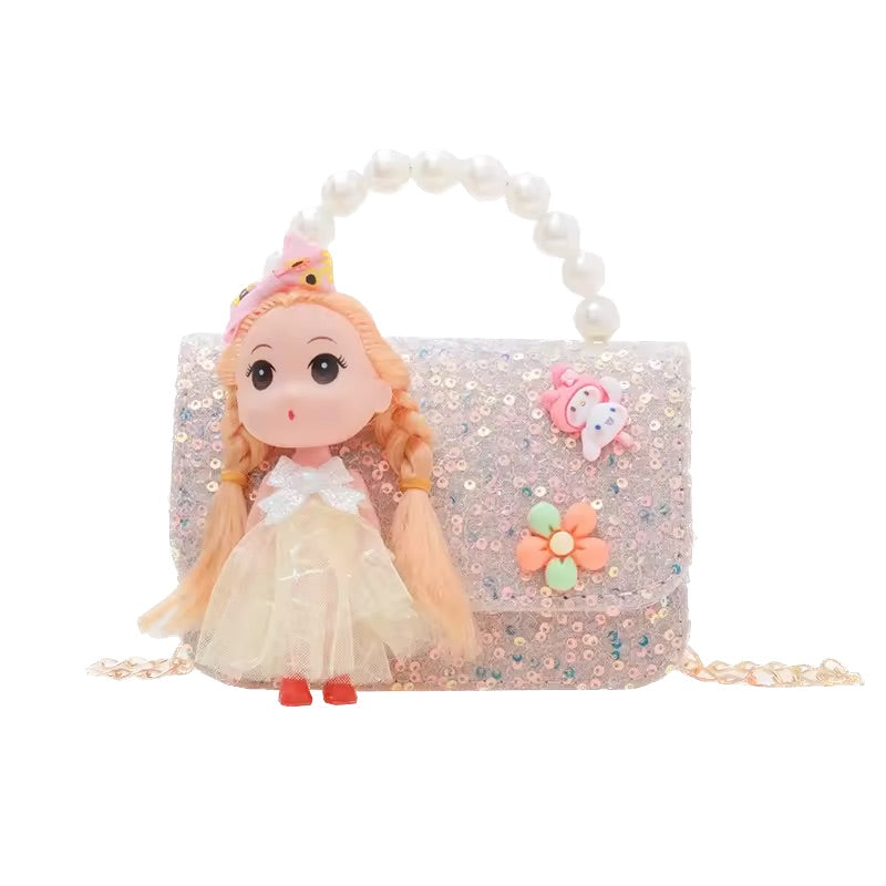 Small doll with blonde hair and a beige dress sitting on a glittery handbag with floral decorations.