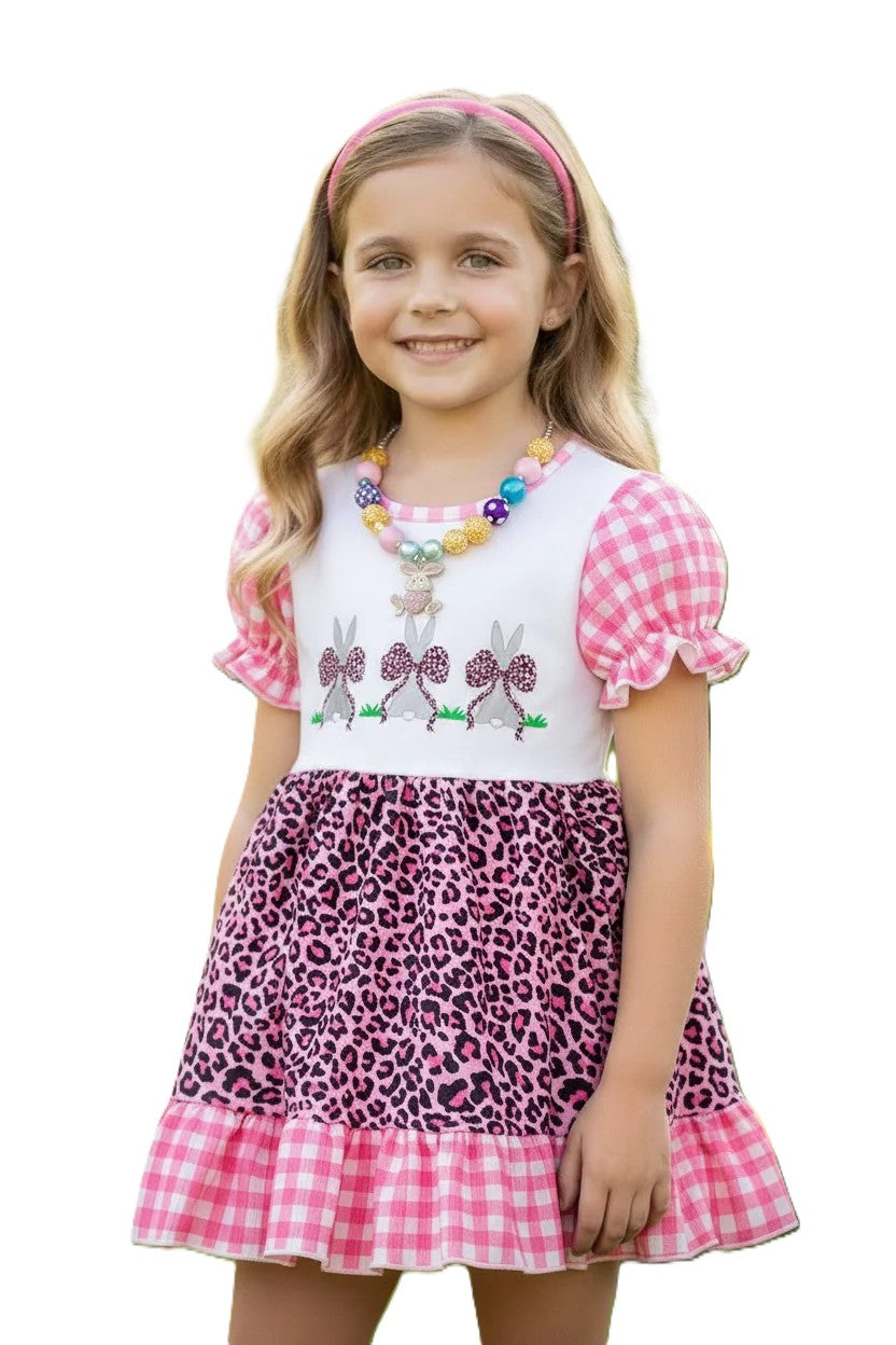 Young girl wearing a dress with pink checkered sleeves, white top with bunny design, and leopard print skirt on a white background.