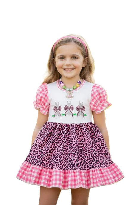 Young girl wearing a pink and purple dress with a checkered skirt on a white background