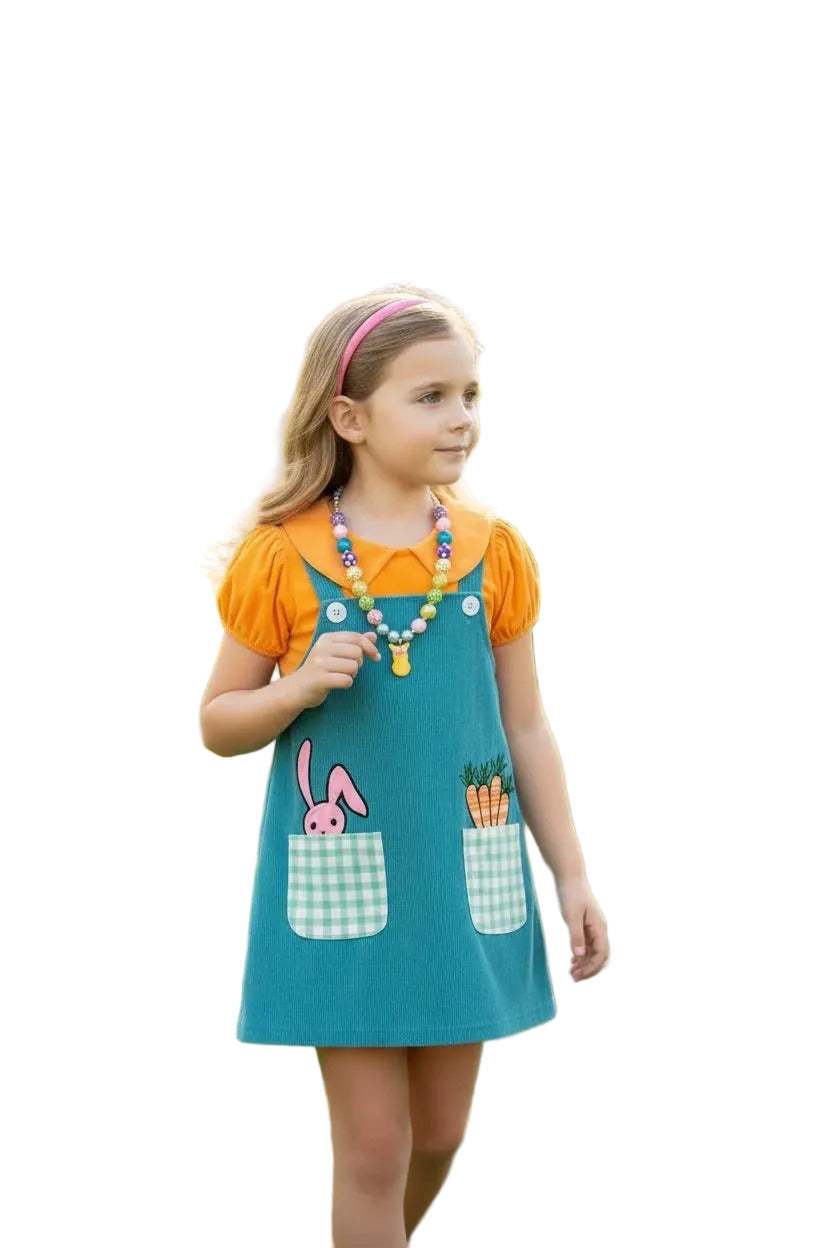 Young girl in a colorful dress with bunny design standing in a garden.