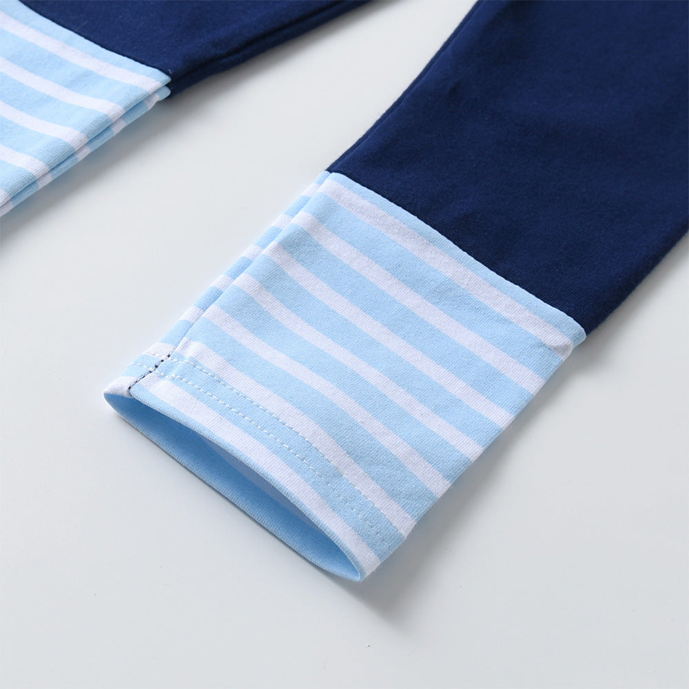 Close-up of navy pants with light blue and white striped cuffs on a light gray background
