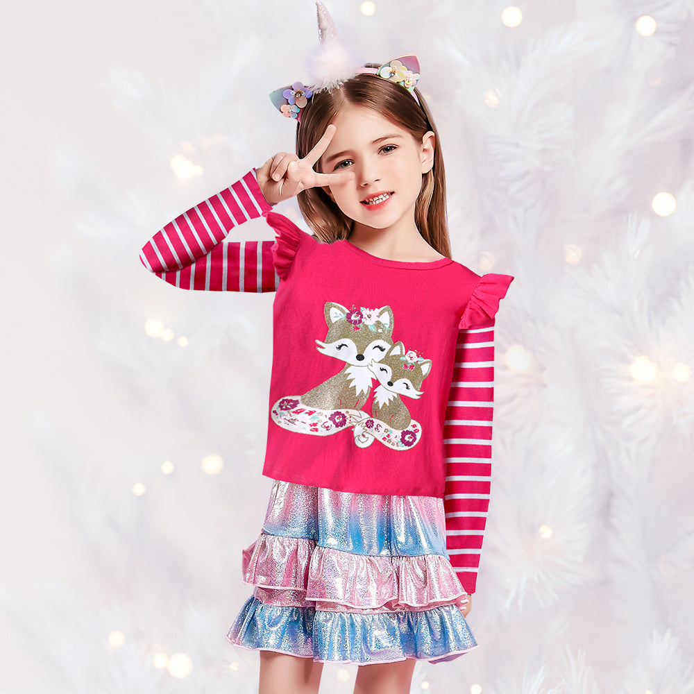 Young girl wearing a pink dress with a fox design and striped sleeves, against a white background with small lights.