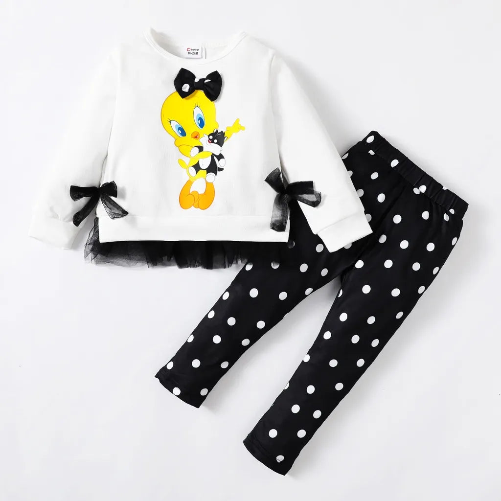 A toddler outfit with a white t-shirt featuring a cartoon character and black pants with a polka dot pattern.