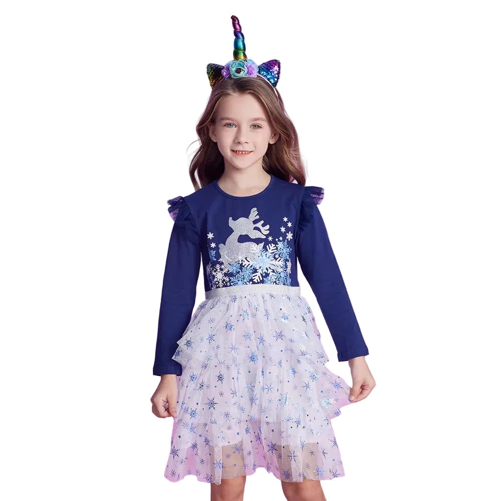 Young girl in a blue dress with a unicorn design, standing against a pink background with a balloon and gift box.