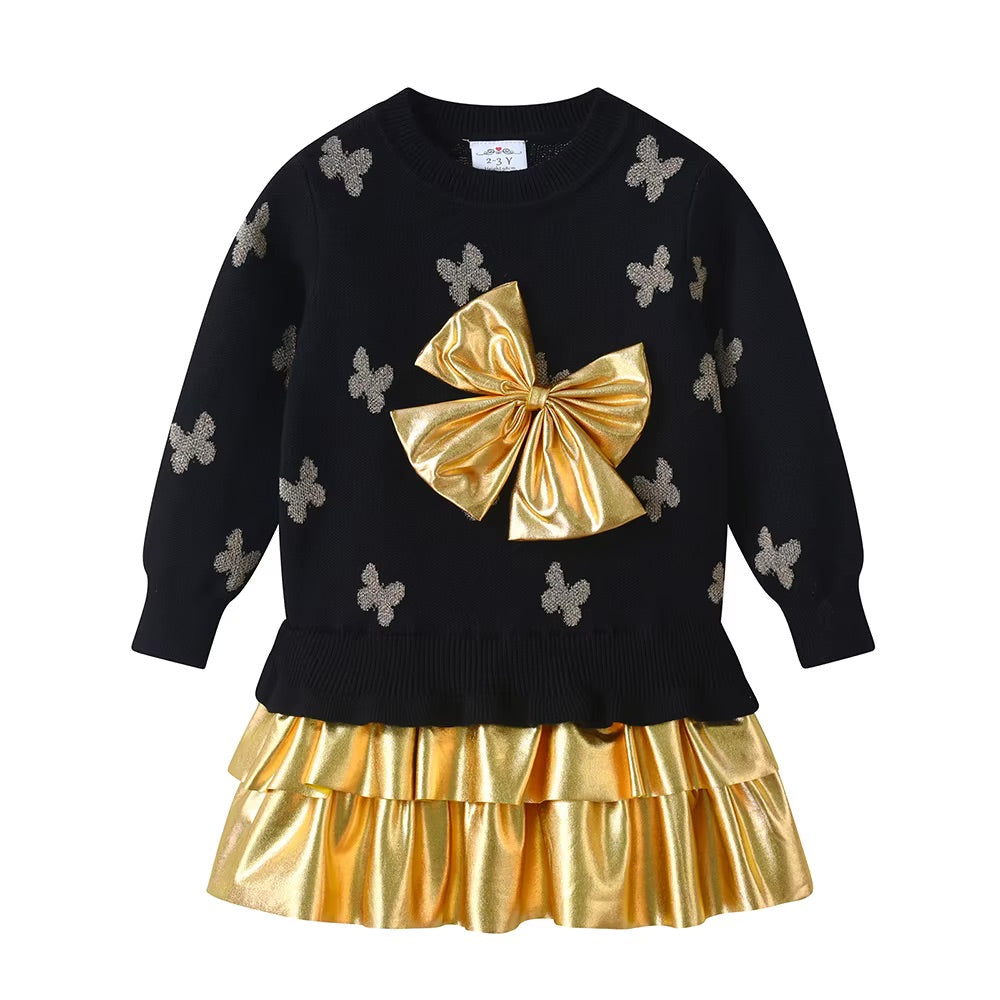 Black sweater with butterfly patterns and a gold bow, paired with a matching gold skirt on a white background.
