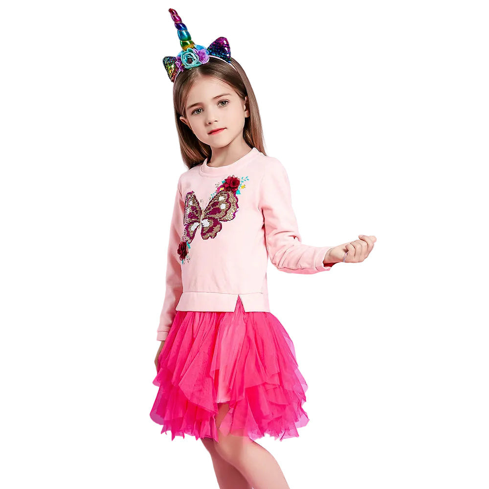 Young girl in a pink outfit with a butterfly design and colorful unicorn horn headband on a white background