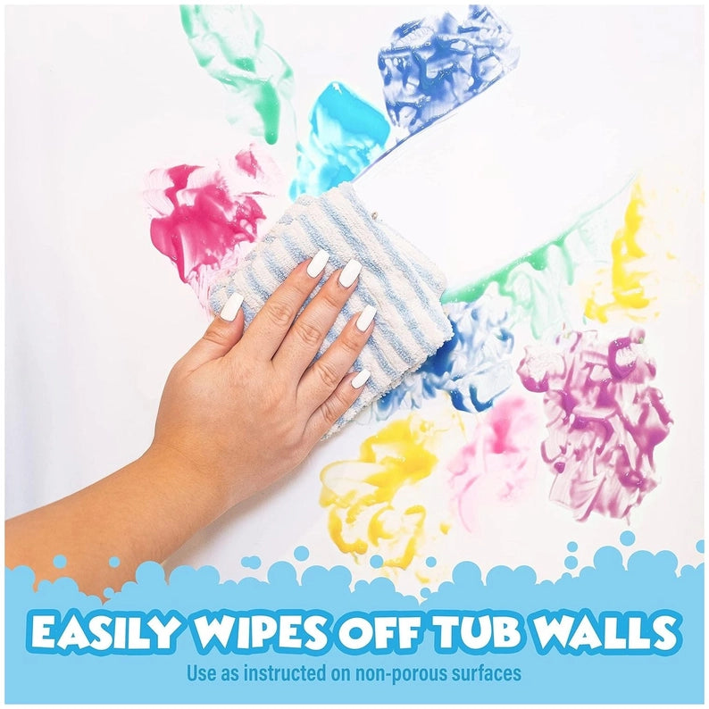 Hand using a scrubber to clean colorful paint splashes off a surface.