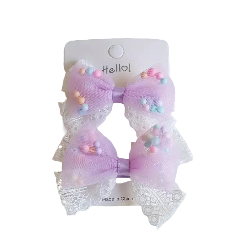 A set of two hair clips with lace bows and colorful pastel bubble decorations, attached to a white card.