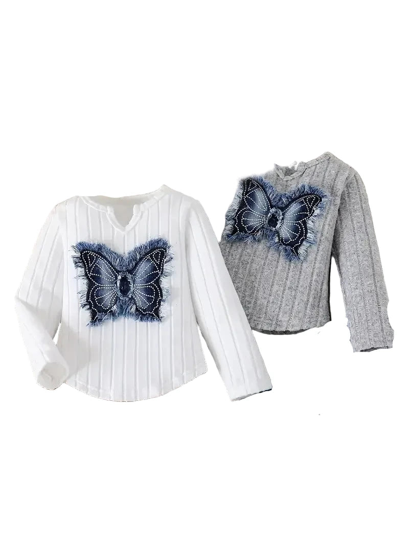 Two sweaters with butterfly designs on a round wooden table.