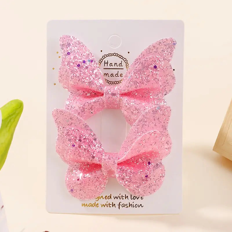 A set of pink butterfly-shaped hair clips with glitter, displayed on a card with the text 'Hand made' and 'with love made with fashion'.