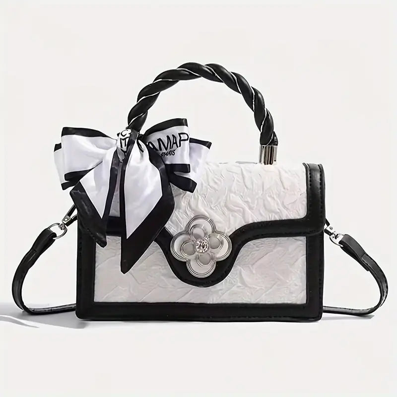 White handbag with black accents and decorative elements on a light gray background