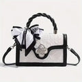 White handbag with black accents and decorative elements on a light gray background