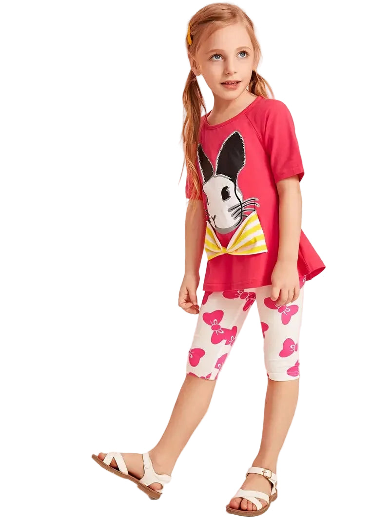 Young girl wearing a red shirt with a bunny design and white leggings with pink hearts on a white background