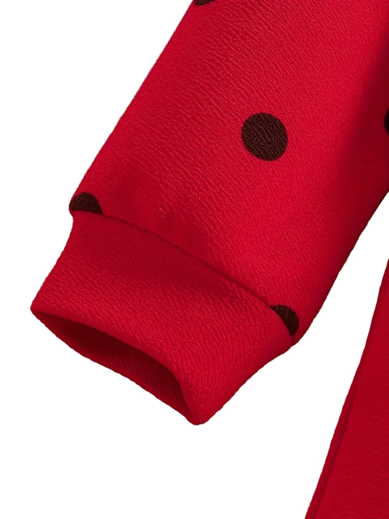 Close-up of a red garment with black polka dots on a wooden surface