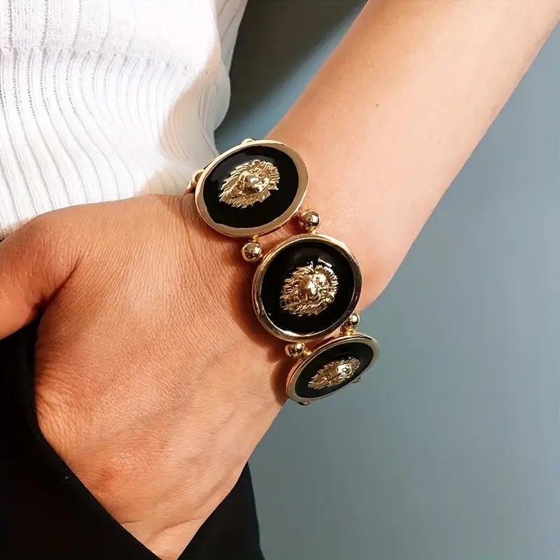 Bracelet with lion head designs on a wrist against a neutral background