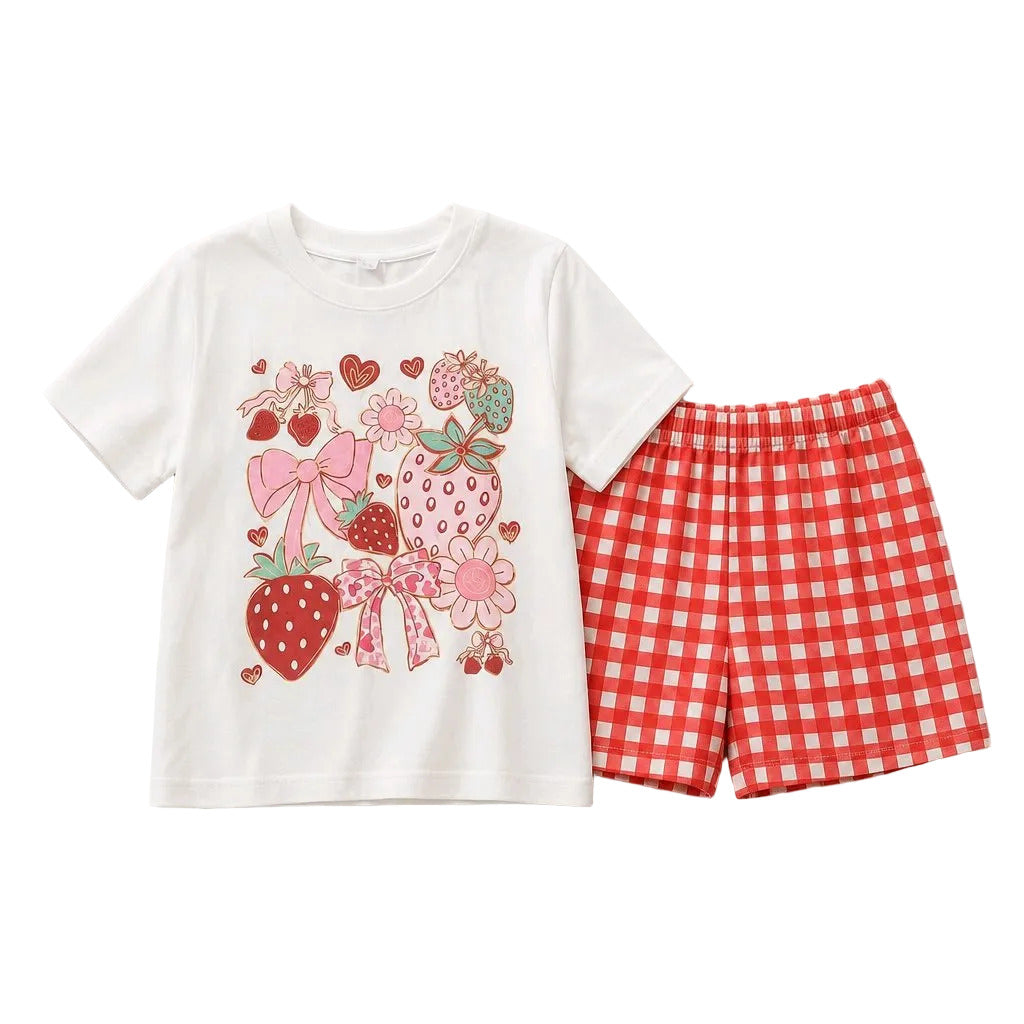 A children's two-piece outfit set featuring a white short-sleeve T-shirt with a colorful strawberry and bow graphic print, paired with red and white gingham check shorts, laid flat on a light gray background.