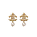 Gold Chanel earrings with pearl drops on a light gray background