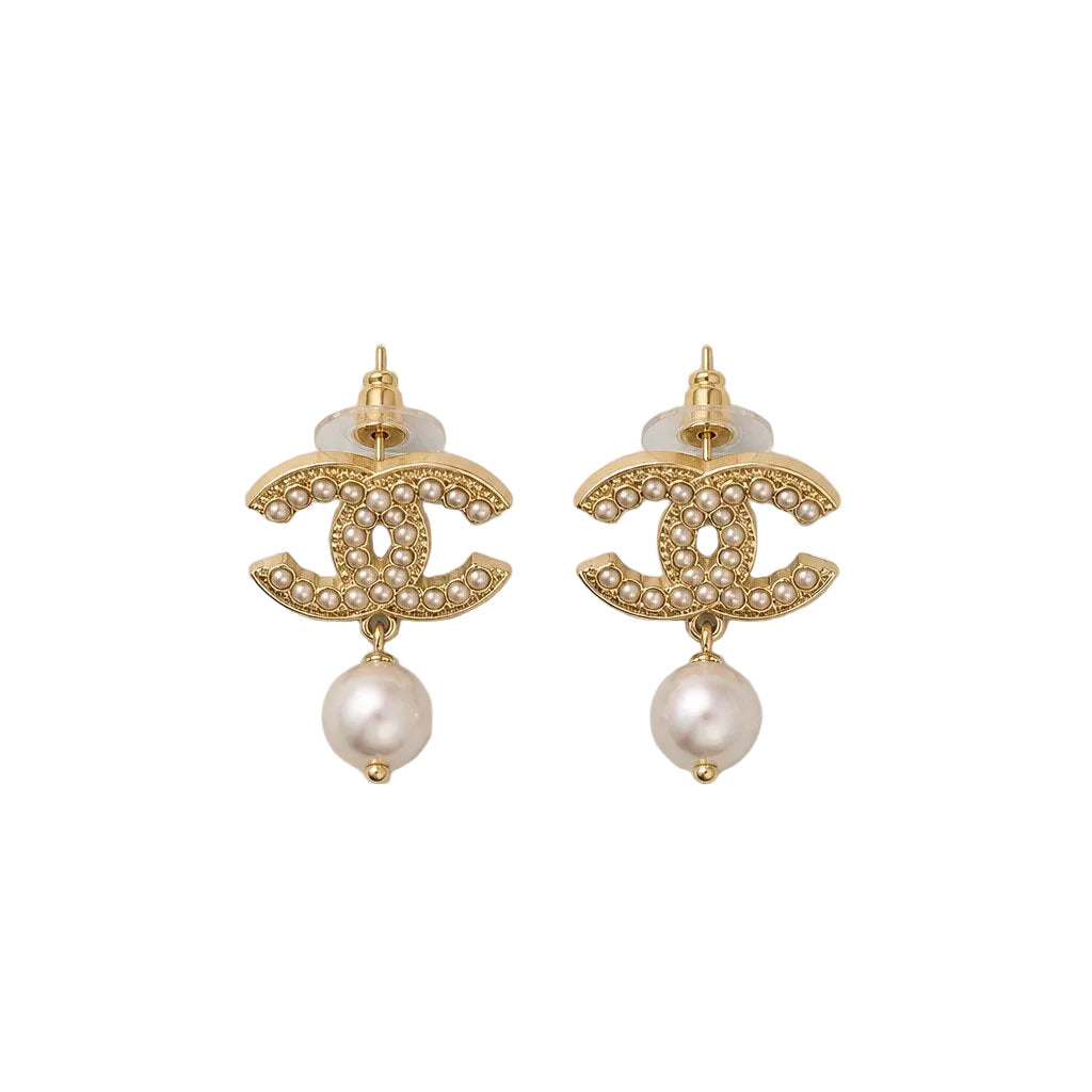 Gold Chanel earrings with pearl drops on a light gray background