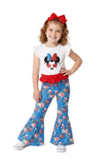 Young girl wearing a white shirt with a cartoon character and blue floral pants on a white background