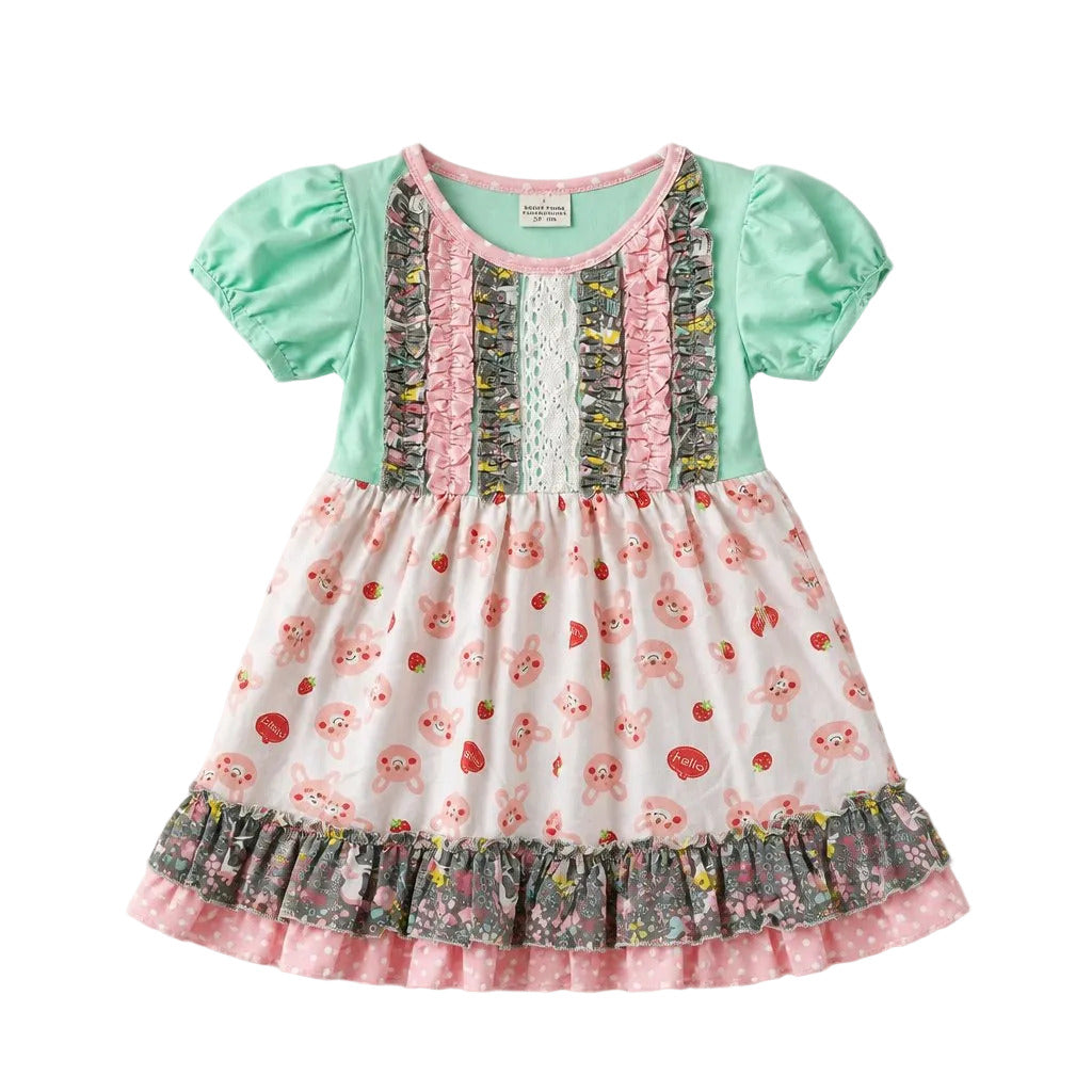 A baby girl's short-sleeve dress with a mint green bodice, pink ruffle trim, and a white skirt printed with pink cherubs and red strawberries, finished with a ruffled hem.
