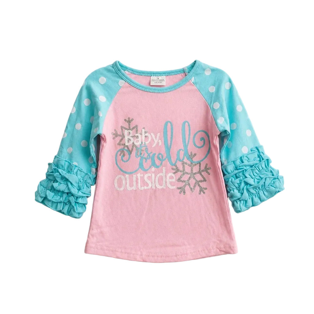 A toddler girl's long-sleeve raglan shirt with a pink body, light blue sleeves with white polka dots, and ruffled cuffs. The front features the text 'Baby it's cold outside' in blue and white script with silver glittery snowflakes.