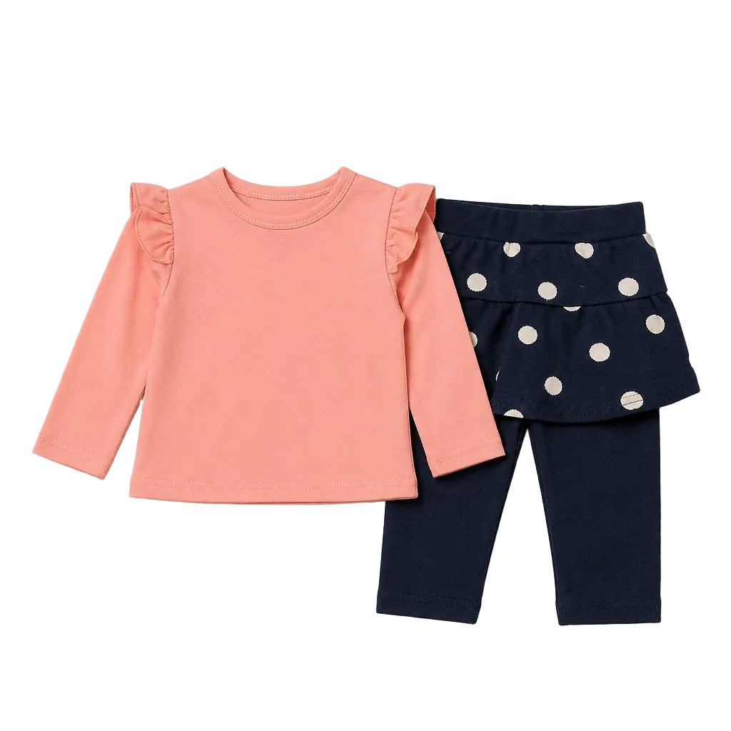 A toddler girl's two-piece outfit set featuring a coral pink long-sleeve top with ruffle details on the shoulders, paired with navy blue leggings and a matching navy blue ruffled skirt with white polka dots.