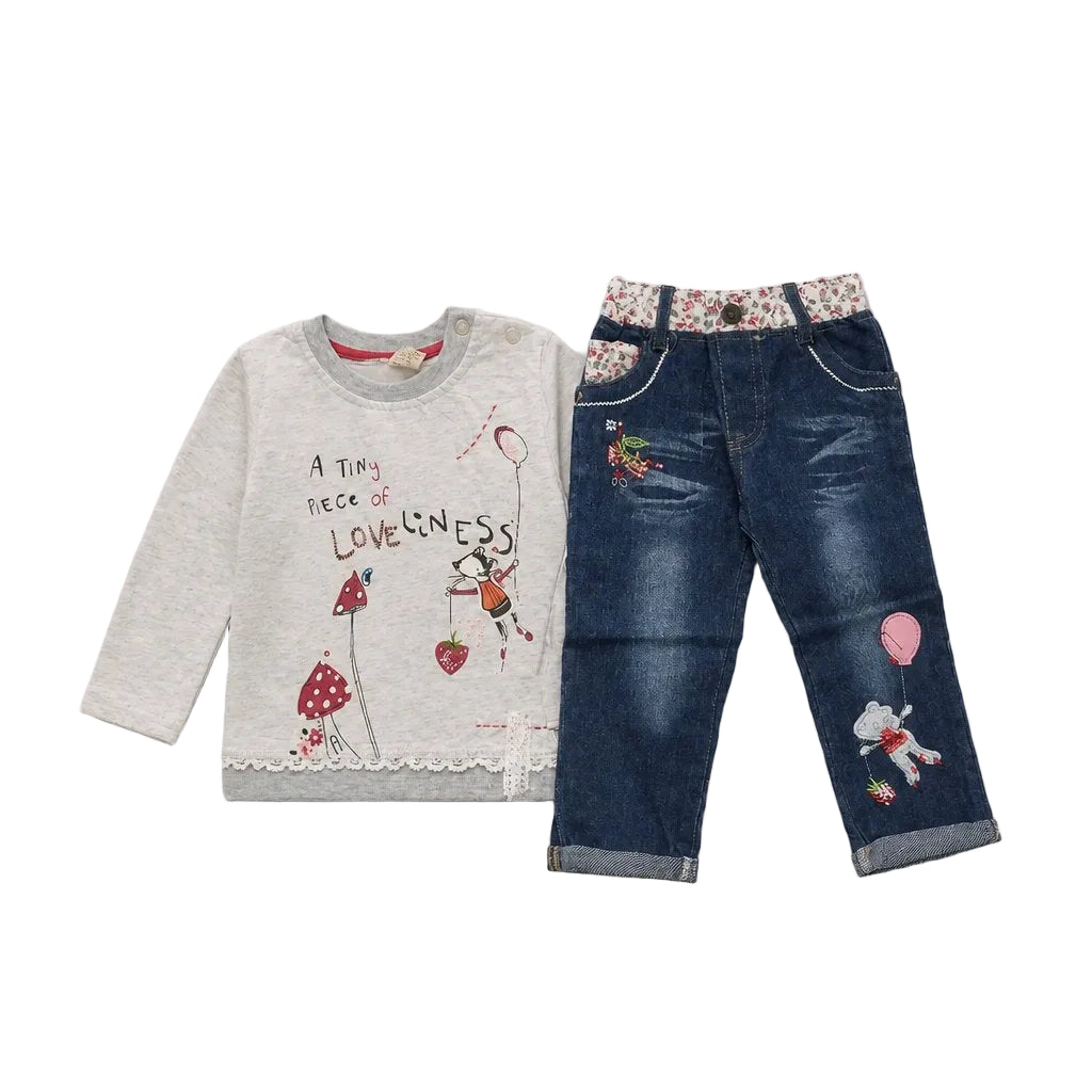 A children's two-piece outfit set featuring a light gray long-sleeve top with whimsical cartoon graphics and text, paired with dark blue denim jeans that have floral waistband detailing and cartoon patches on the legs.