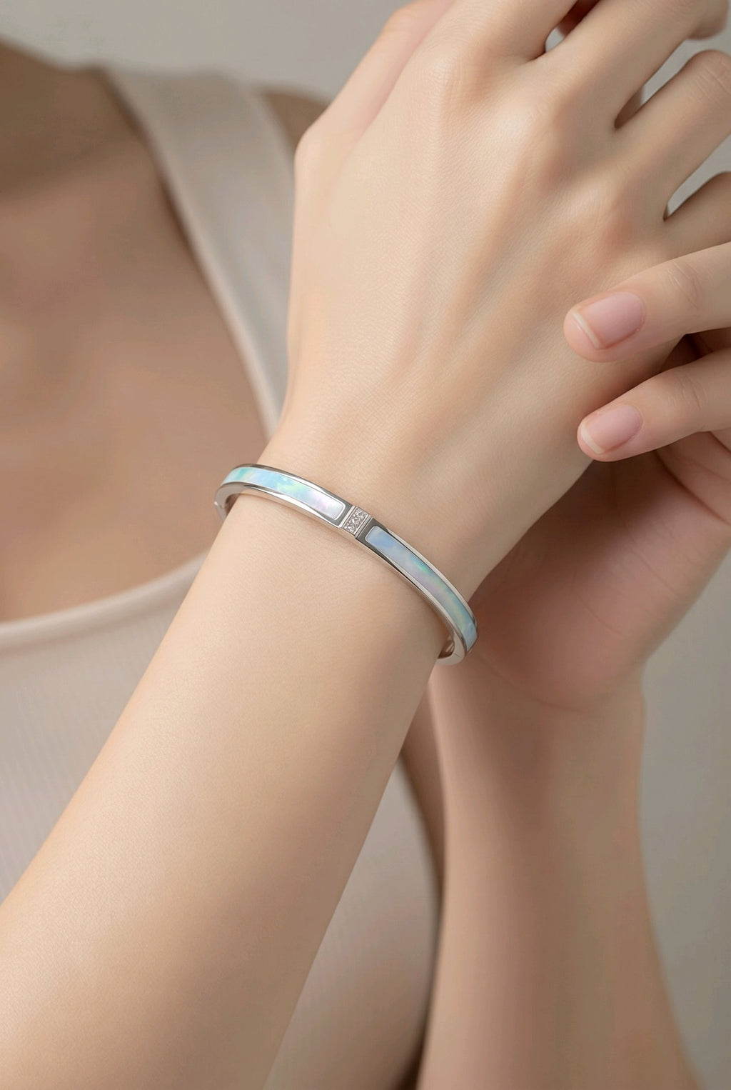 Silver bracelet on a wrist with a neutral background