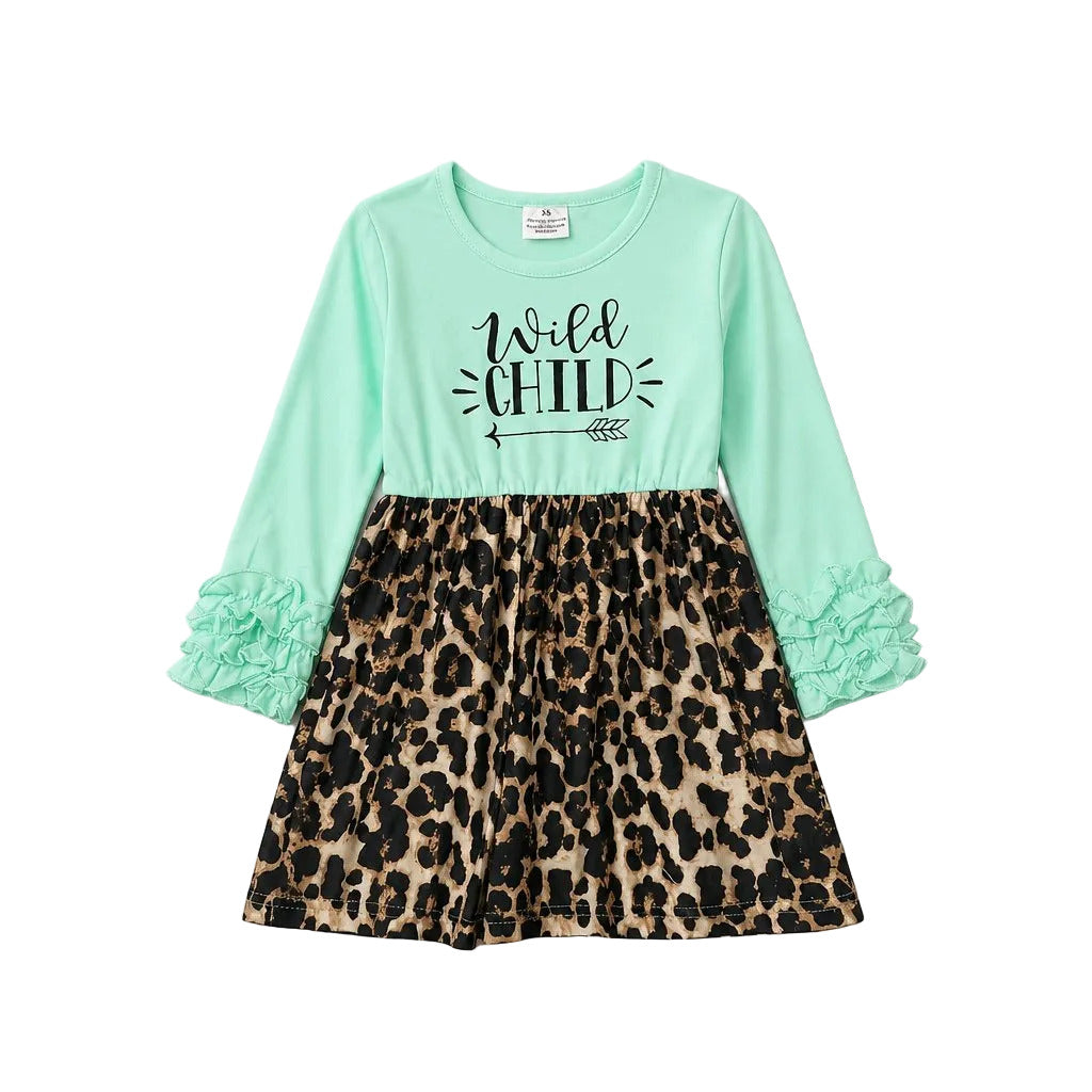 A girls' long-sleeve dress with a mint green top and black 'Wild Child' text graphic, paired with a leopard-print skirt and ruffled cuffs, shown on a neutral gray background.