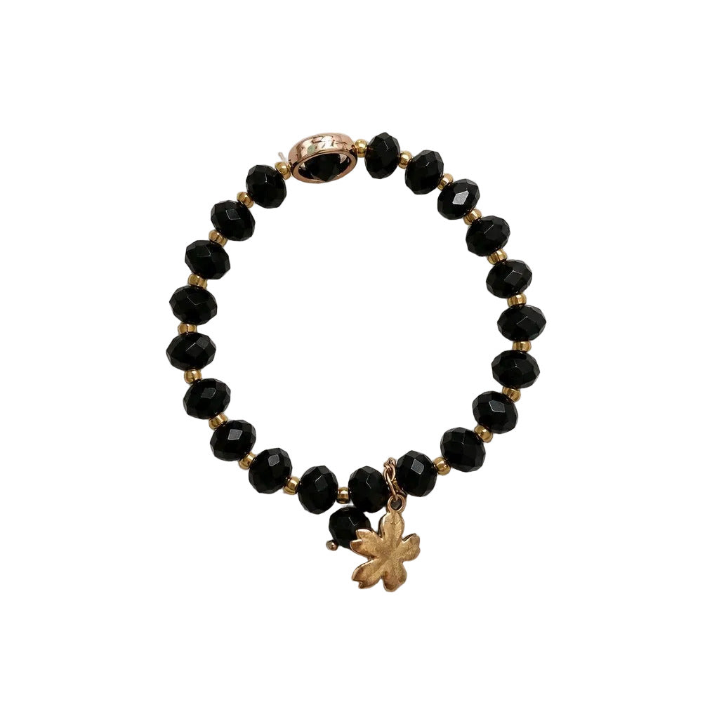 Black beaded bracelet with a gold charm on a light gray background